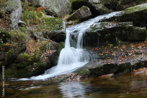 small waterfall hidden in the forest with autumn leaves