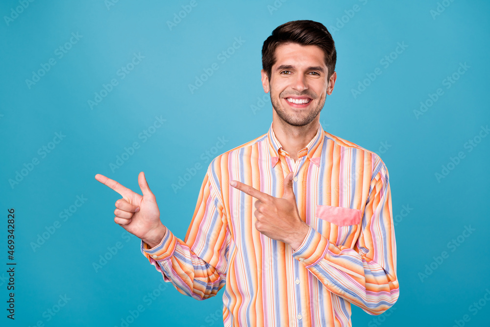 Photo of young handsome man happy positive smile point fingers empty space ad subscribe isolated over blue color background Photo of young handsome man happy positive smile point fingers empty space ad subscribe isolated over blue color background
