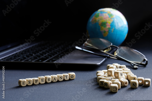 Esperanto inscription next to an open laptop, glasses and globe. The concept of modern technologies in the artificial global language Esperanto. Selective focusing photo