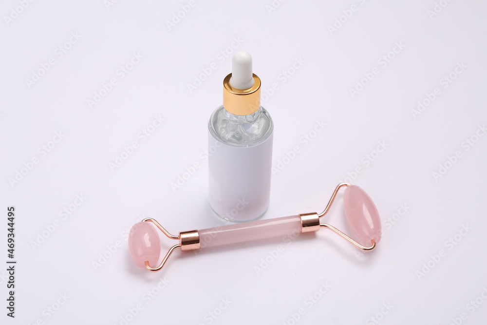 Beautiful composition of mockup serum bottle, pink face roller on white background. Creative trendy beauty layout Beautiful composition of mockup serum bottle, pink face roller on white background. Creative trendy beauty layout