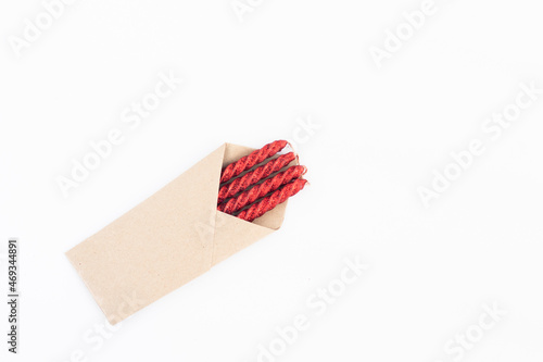 Colorful Glittering Red Candles Packed In Brown Craft Paper. Isolated On White Background With Copy Space For Custom Text
