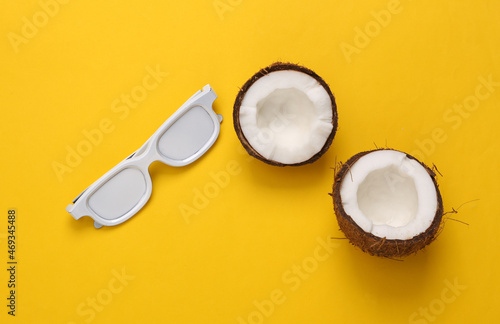 Coconut halves with white glasses on yellow background. Travel concept. Top view