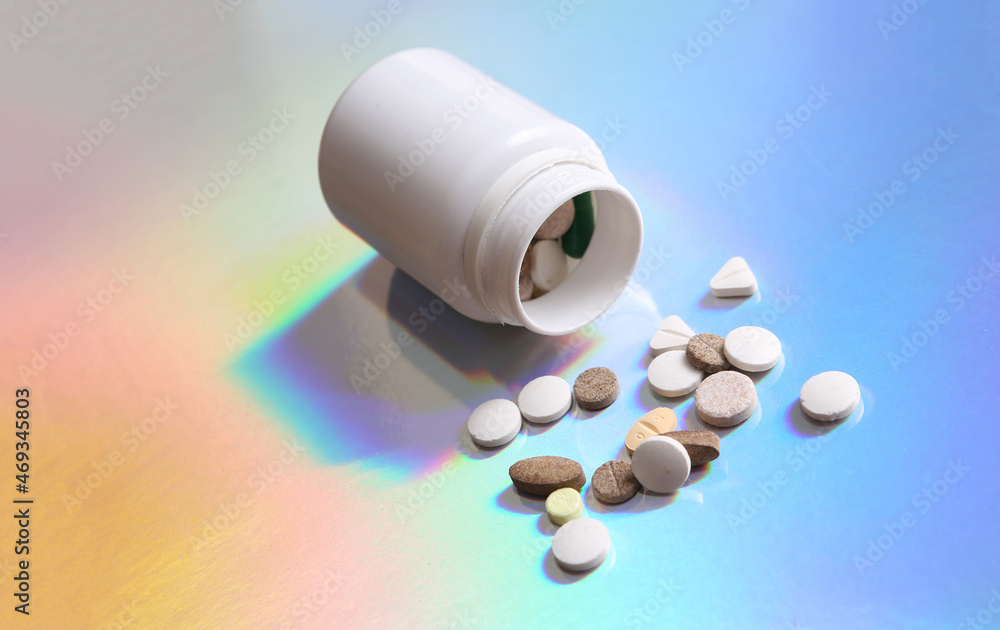 Pills bottle on colored reflective holographic surface Pills bottle on colored reflective holographic surface