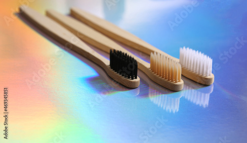 Bamboo rainbow toothbrushes on colored holographic surface