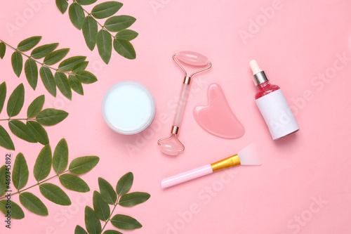 Cosmetic set with sprigs of green leaves on pink background. Natural cosmetics concept
