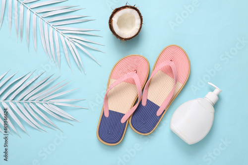 Beach vacation, tripic background. Flip flops with white palm leaves, cream bottle and coconuts on white background. Summer flat lay. Top view photo