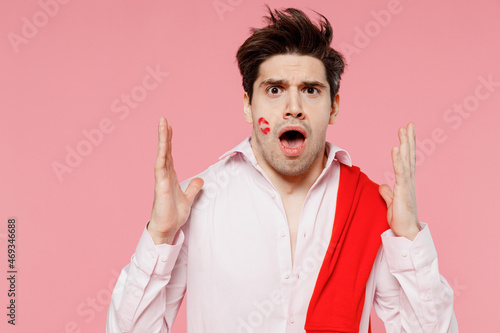 Fototapeta Young sad shocked astonished caucasian man 20s with lipstick lips on face wearing casual shirt sweater spread hands isolated on pink background