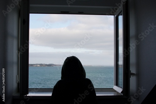 A chid looking the sea from a window