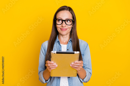 Photo of young lovely woman wondered look empty space workshop tablet isolated over yellow color background