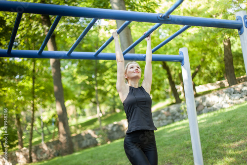 Young beautiful fit woman works out on the workout ground on bright sunny day