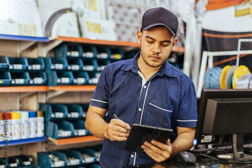 Slika na platnu Young latin man working in hardware store