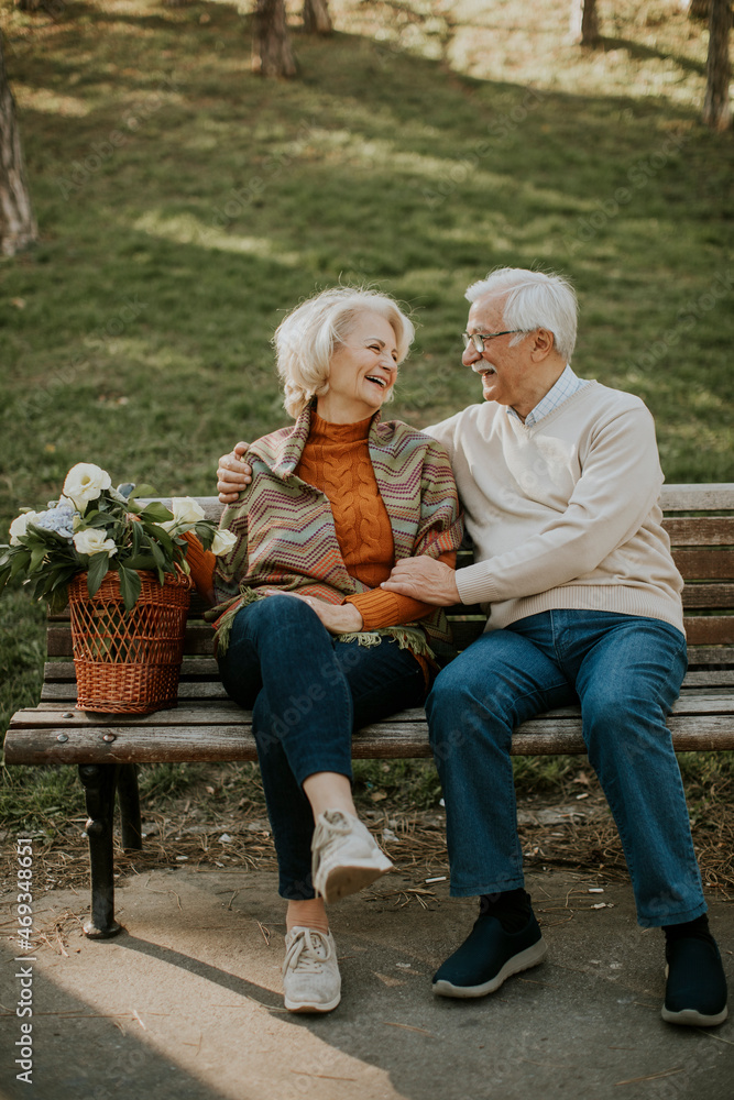 Senior couple sitting on the benchwith basket full of flowers and embracing Senior couple sitting on the benchwith basket full of flowers and embracing