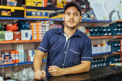 Leinwand Poster Young latin man working in hardware store