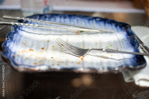 Dirty plate with leftover food crumbs with fork and knife