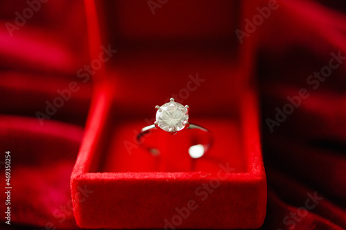 Diamond ring in jewelry gift box on red fabric background © Piman Khrutmuang