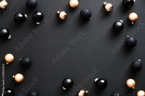 Christmas ornaments on dark black background. Frame made of bronze and black Christmas balls. Flat lay, top view, copy space. Merry Christmas greeting card design, Happy New Year postcard template.