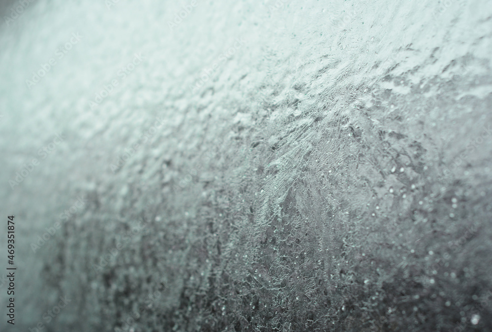 Frozen car window, frozen glass texture. A car window covered with ice in winter.