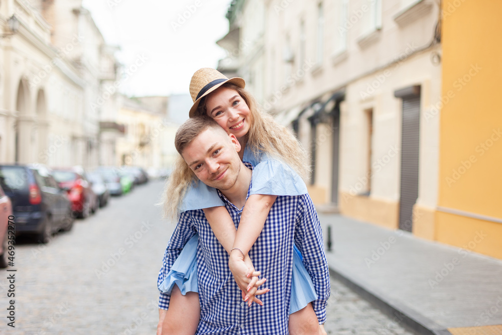 Naklejka premium Enjoying every moment together. Young couple in love having fun outdoors while handsome man giving his girlfriend piggy back ride. Romantic, love concept