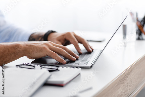 Cropped caucasian millennial man working on laptop and search idea at workplace, side view