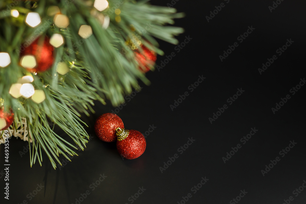 Christmas tree with shiny red festive balls on a black background. Gift and present for the holiday. New and Year and Christmas. Garland and bokeh lights.