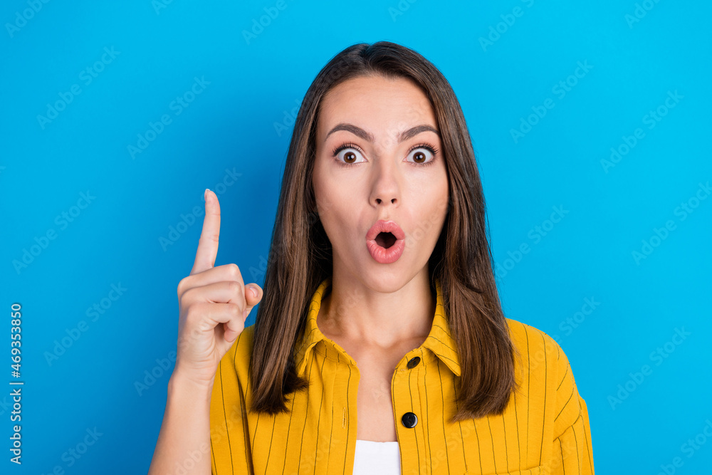 Photo of amazed shocked astonished young woman point finger make solution isolated on blue color background Photo of amazed shocked astonished young woman point finger make solution isolated on blue color background