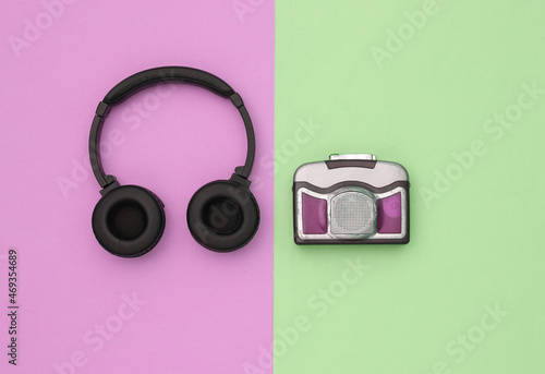 Mini audio cassette player with stereo headphones on colored background. Top view