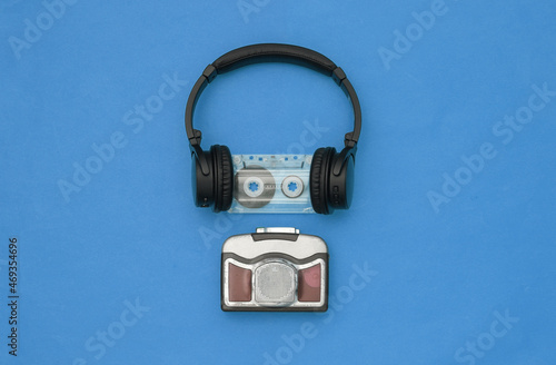 Mini audio player with stereo headphones on blue background. Top view