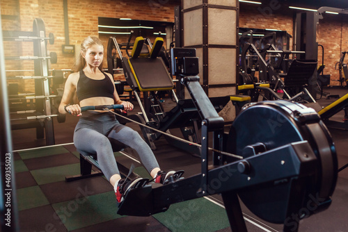 Athletic woman training on the rowing machine in gym