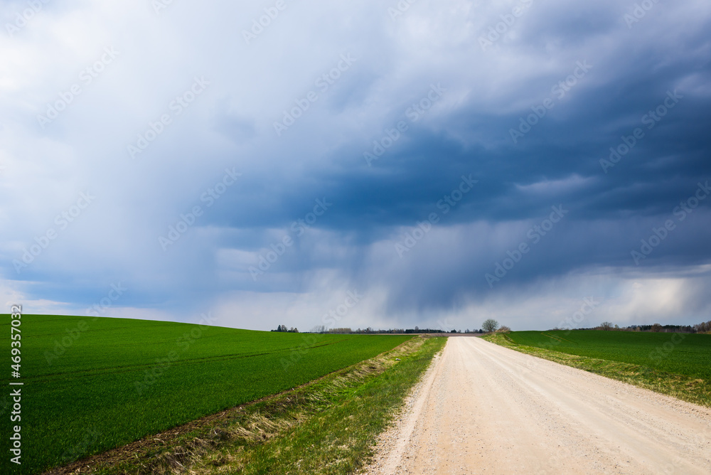 Selective focus photo. Dark clouds above agriculture field and hill.