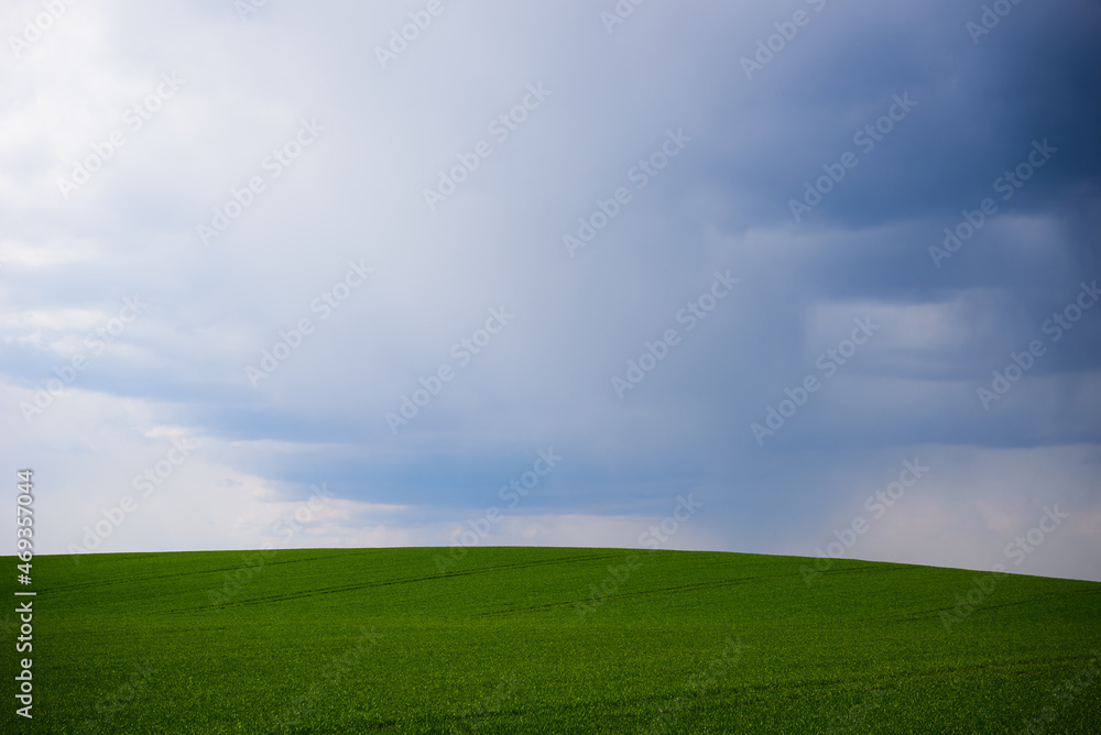 Selective focus photo. Dark clouds above agriculture field and hill.