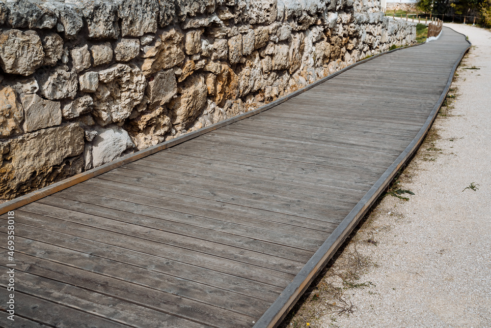 A wooden path going far ahead. The path to the sea, the sandy shore, the fence and the fence of stone. Walk in the fresh air, equipped sea area A wooden path going far ahead. The path to the sea, the sandy shore, the fence and the fence of stone. Walk in the fresh air, equipped sea area