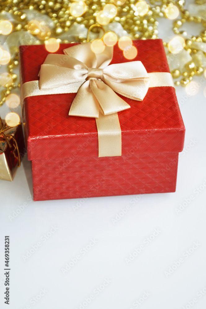 Obraz premium A red gift box. golden beads for decoration and bokeh. Background for decoration for Christmas and New Year. winter holidays.