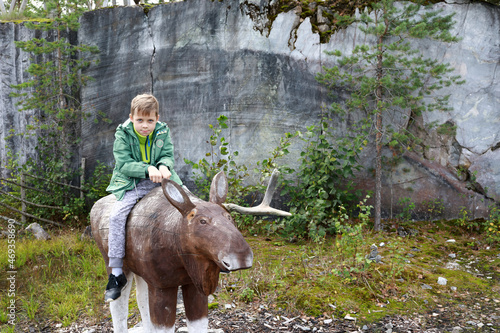 Child sitting on wooden Elk photo