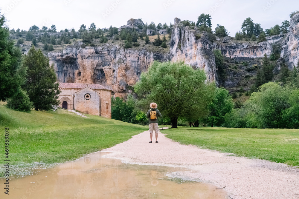 Fototapeta premium Panoramic view of unrecognizable man walking isolated in nature with backpack. Horizontal view of man traveling alone in the Lobos river canyon in Soria. People and travel destinations in Spain.