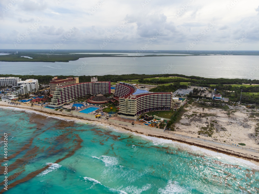 Fototapeta premium Aerial photograph. The resort town, many high-rise buildings, hotels, swimming pools. Sandy shore. The sea near the coast is polluted with algae. Environmental protection.