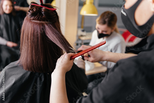 Hairdresser cutting client's hair in beauty salon.