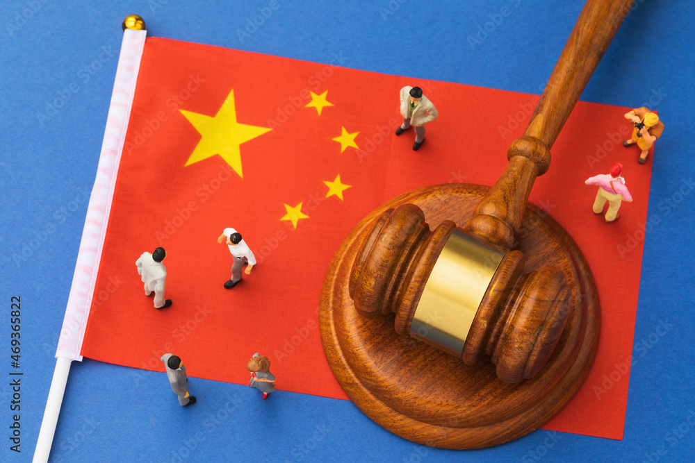 Judicial hammer, flag of China and plastic toy men on blue background, concept of litigation in Chinese society