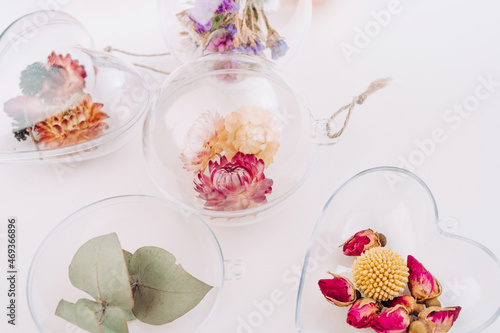 DIY ornaments filled with dried flowers on white background