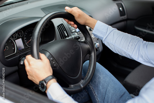 Unrecognizable businessman driving comfy auto  holding hands on steering wheel