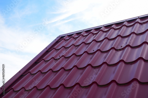 Part of a red corrugated metal roof against a blue sky. On the left is the place to insert the inscription