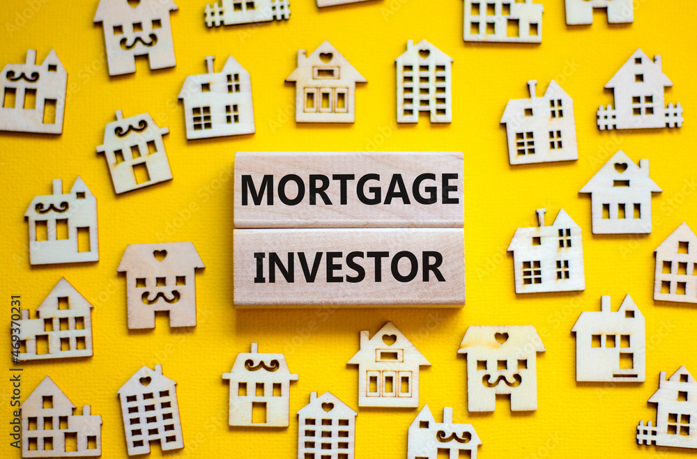 Mortgage investor symbol. Concept words 'Mortgage investor' on wooden blocks near miniature wooden houses. Beautiful yellow background. Business, mortgage investor concept.