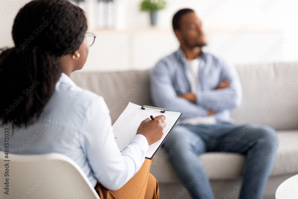 Young black man with mental problem having session with psychotherapist at medical office, selective focus Young black man with mental problem having session with psychotherapist at medical office, selective focus