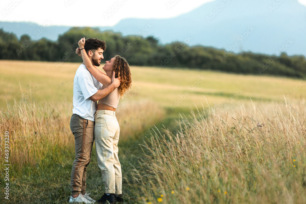 Lovely heterosexual couple in a grass field walking and kissing Lovely heterosexual couple in a grass field walking and kissing