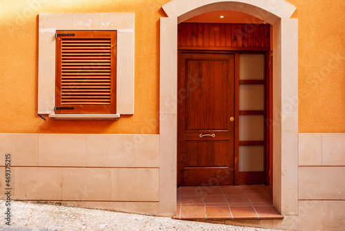 Wooden vintage window with red shutters and a door on a plastered stone wall in the Spanish style.