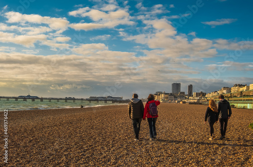 View of mature couple and their teenage children walking on the beach in English seaside town 