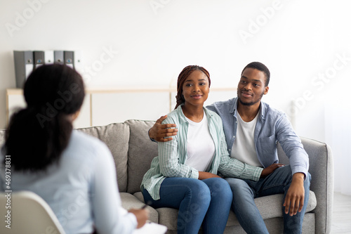 African American married couple hugging after effective psychotherapy at marital counselor's office photo