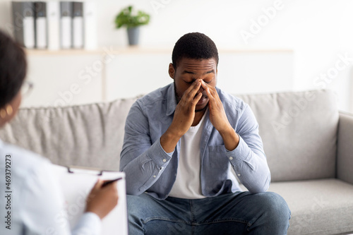 Stressed black guy having session at psychologist's office, receiving professional help in solving personal problems