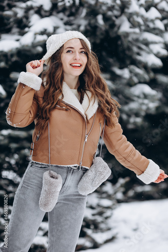 Happy smiling girl in a winter park looking at camera wearing a warm jacket