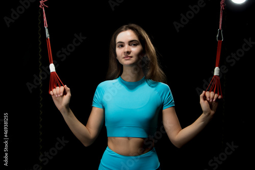 Alfagravity training, a new sport. Young athletic woman in sports clothing training legs with Alfagravity fitness straps in the gym. High quality photo
