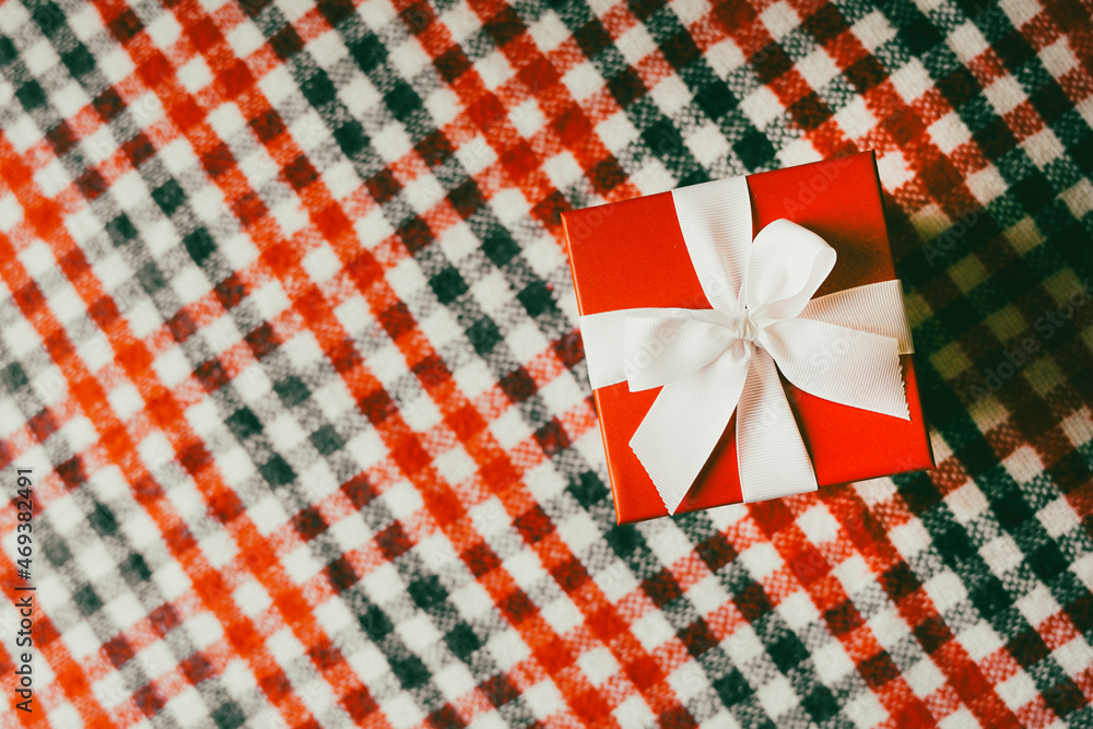 Obraz premium Plaid woolen fabric and Christmas gift. Top view.